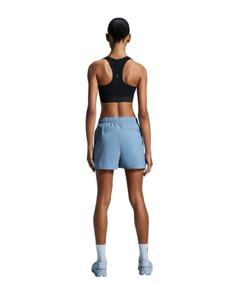 Person wearing a black sports bra and light blue shorts on a white background