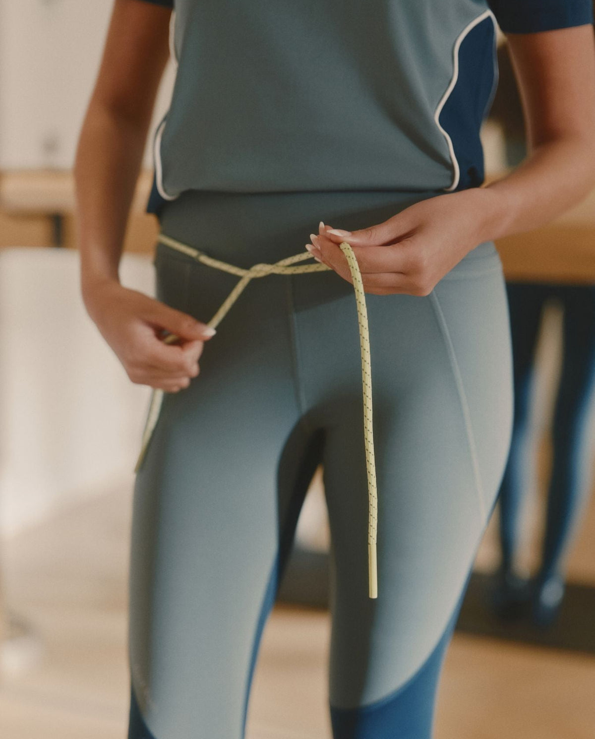 Person wearing a blue and gray athletic outfit holding a rope.