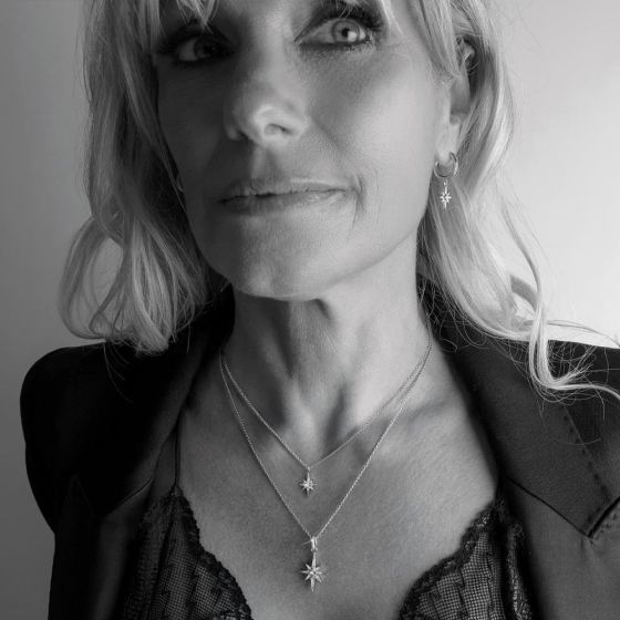 Woman wearing jewelry with star charms. Black jacket and lace top. Black and white image. 
