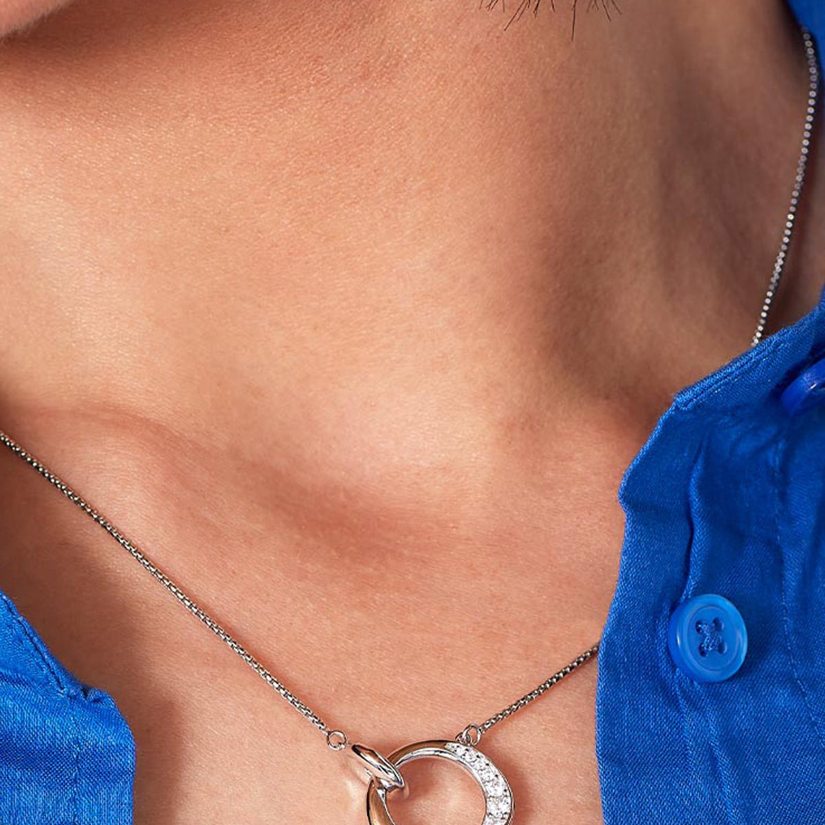 Close-up showcasing Kit Heath Bevel Cirque necklace. Silver chain, circle pendant with pave CZ detail. Perfect jewelry gift.