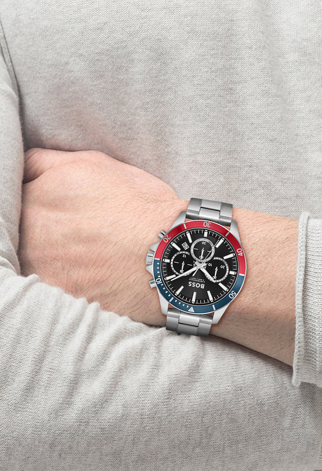 A stainless steel BOSS Troper chronograph watch on a wrist, displaying its black dial and red and blue bezel details.