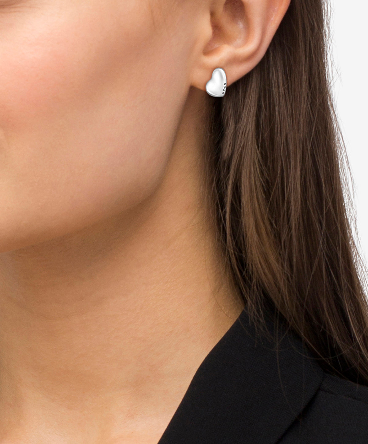 Close-up of woman wearing BOSS heart earrings, showcasing the sleek stainless steel design and ear stud style.
