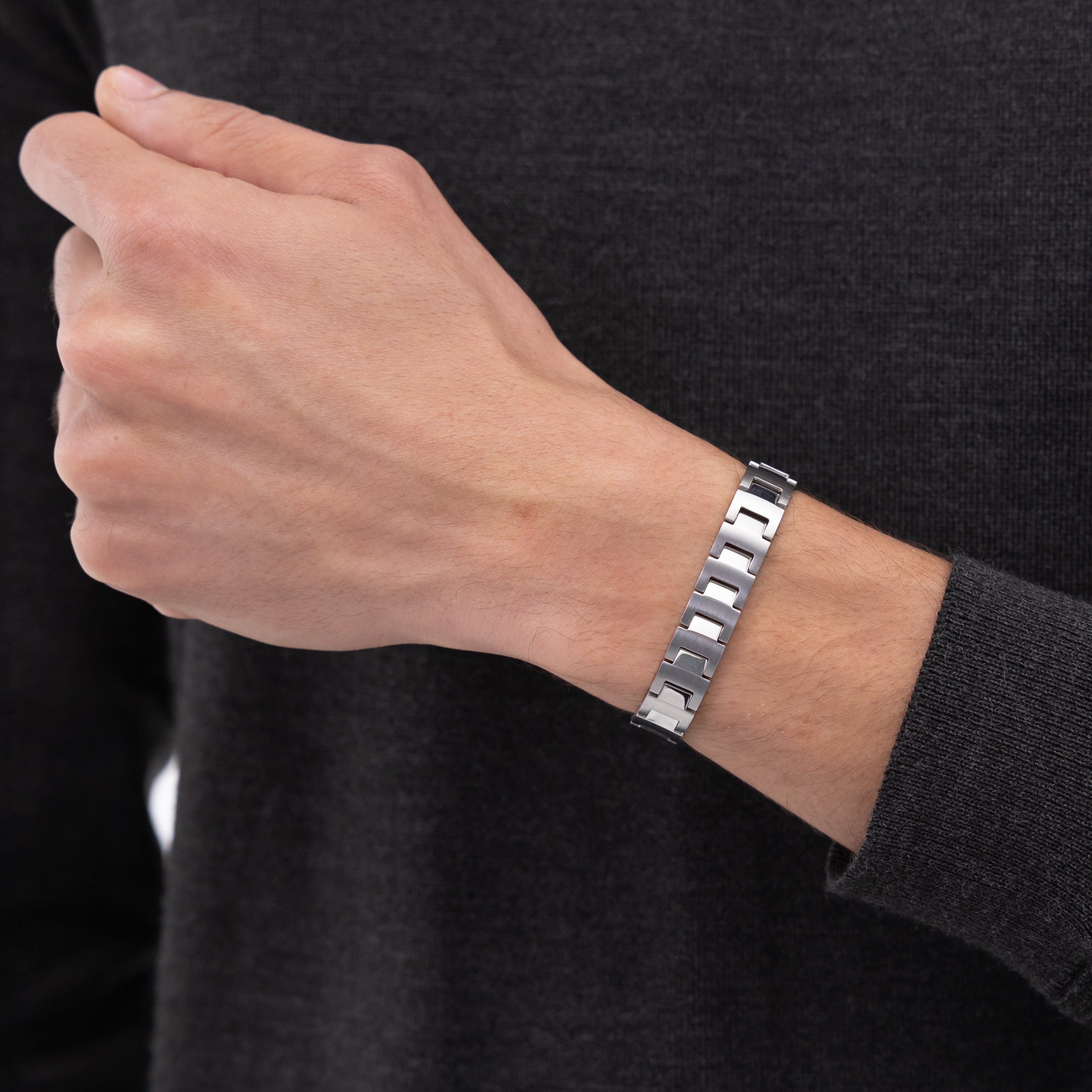 Silver bracelet on a person's wrist, gray sweater.
