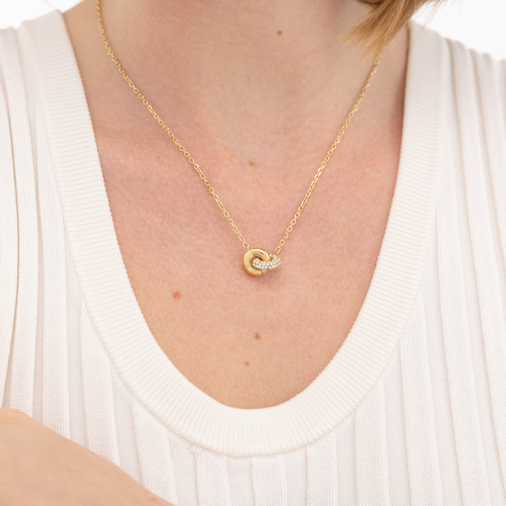 Gold necklace with interlocking rings and diamonds, white ribbed top.