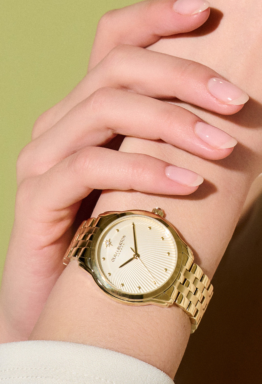 Close-up of a woman's wrist wearing an Olivia Burton gold-plated bracelet watch. Showcases the watch's design and fit.