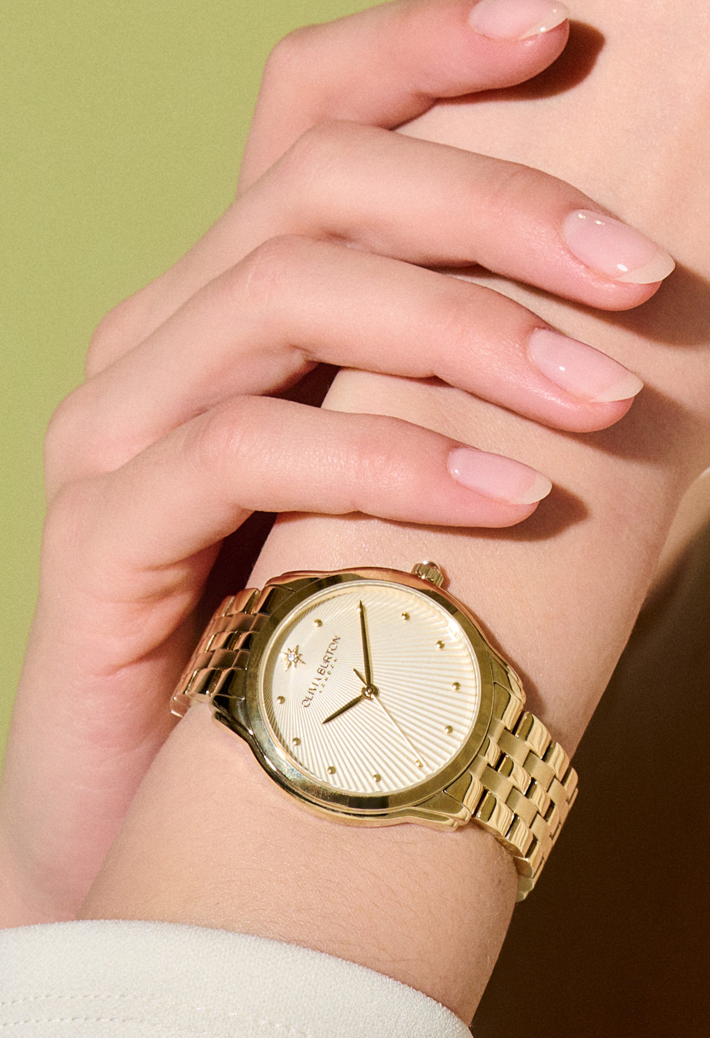 Close-up of a woman's wrist wearing an Olivia Burton gold-plated bracelet watch. Showcases the watch's design and fit.