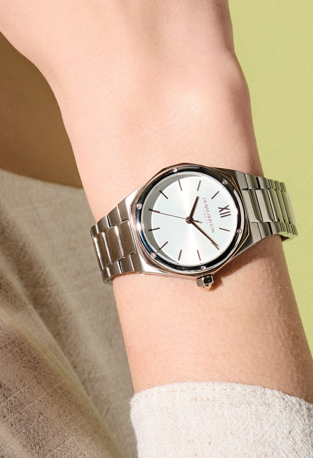 Close-up showcases the Olivia Burton Sports Luxe Hexa two-tone watch on a wrist. Details bracelet & face.