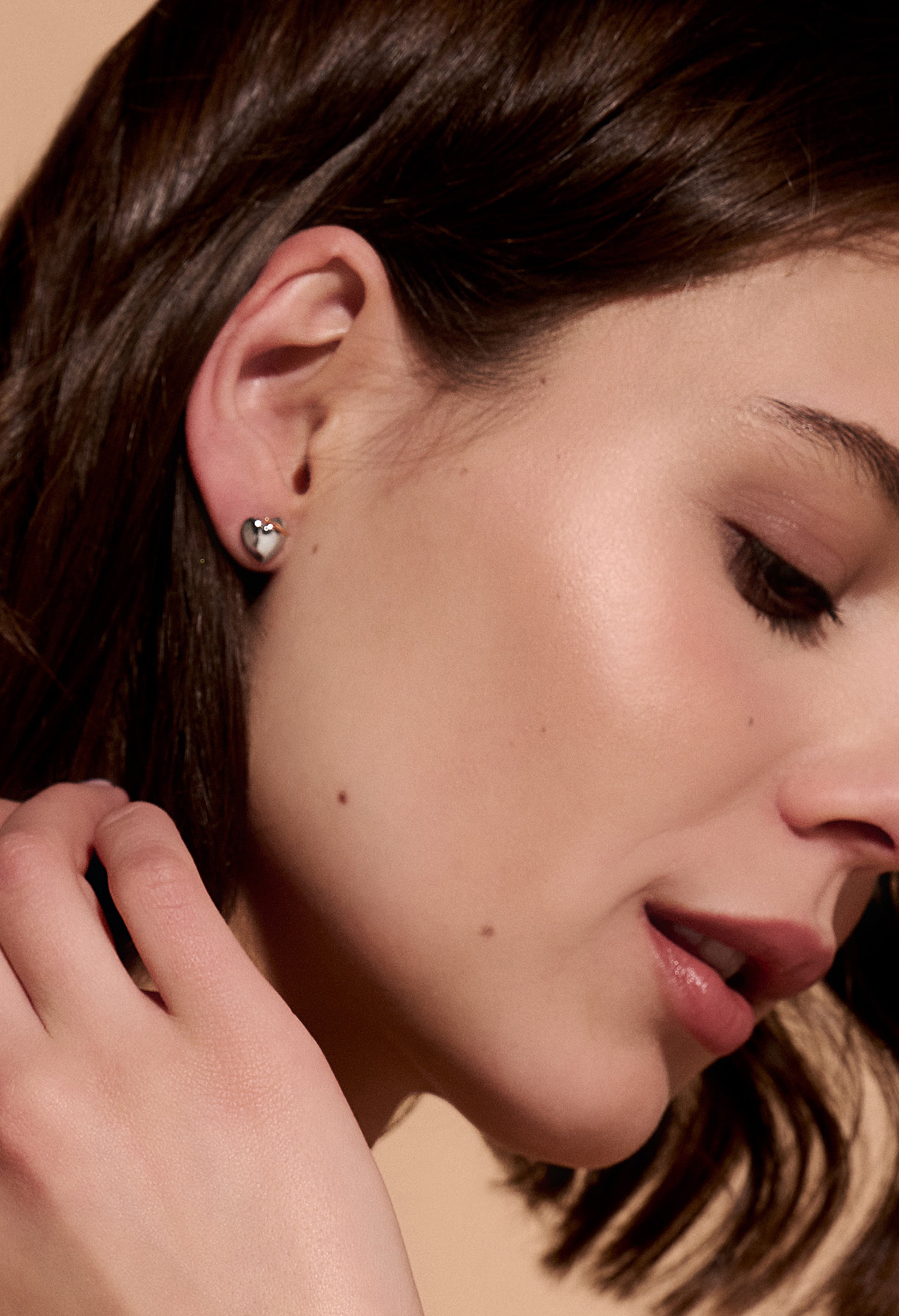 Close-up of model wearing Olivia Burton knot heart earrings, showcasing the jewelry's design and fit.