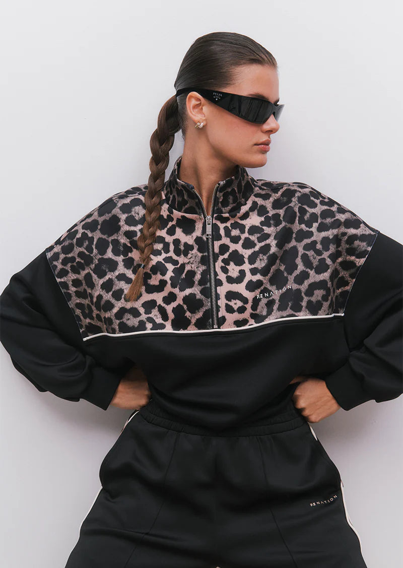 Person wearing a black and leopard print tracksuit against a white background