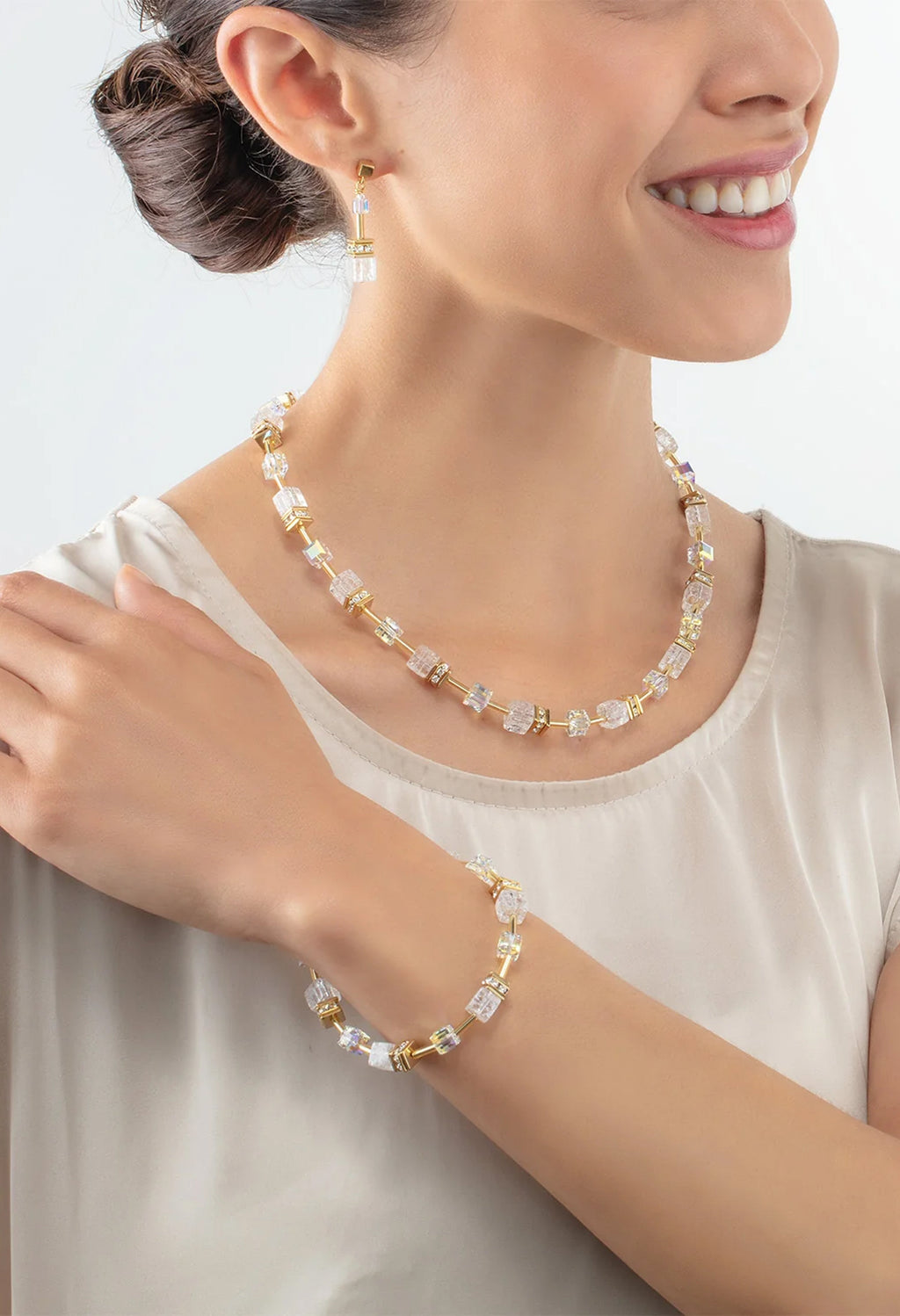 Woman wearing GeoCube Rock Crystal earrings, necklace, and bracelet jewelry set, gold plated.