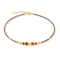 A brown choker with gold trim and decorative beads.
