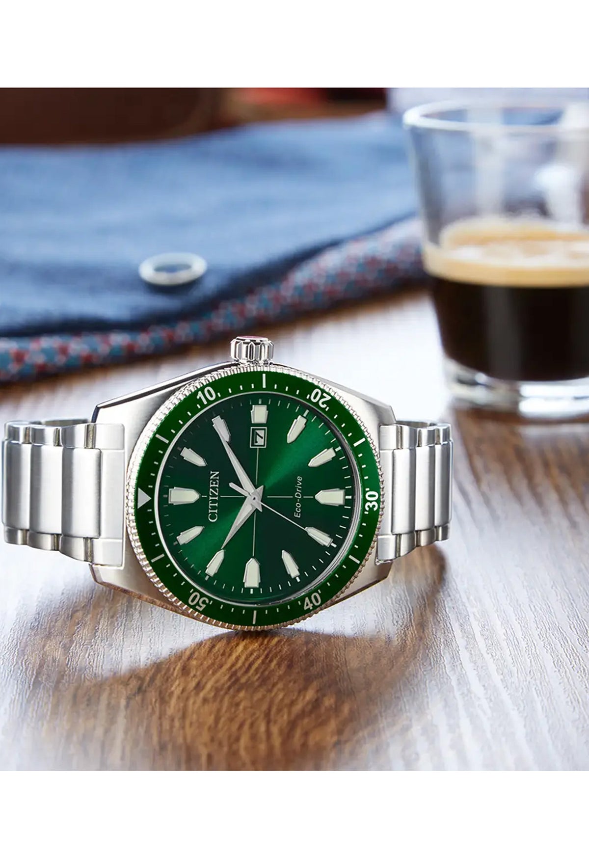 Citizen Eco-Drive watch, featuring a green dial, date display, & stainless steel band. Showcases the Sport design.