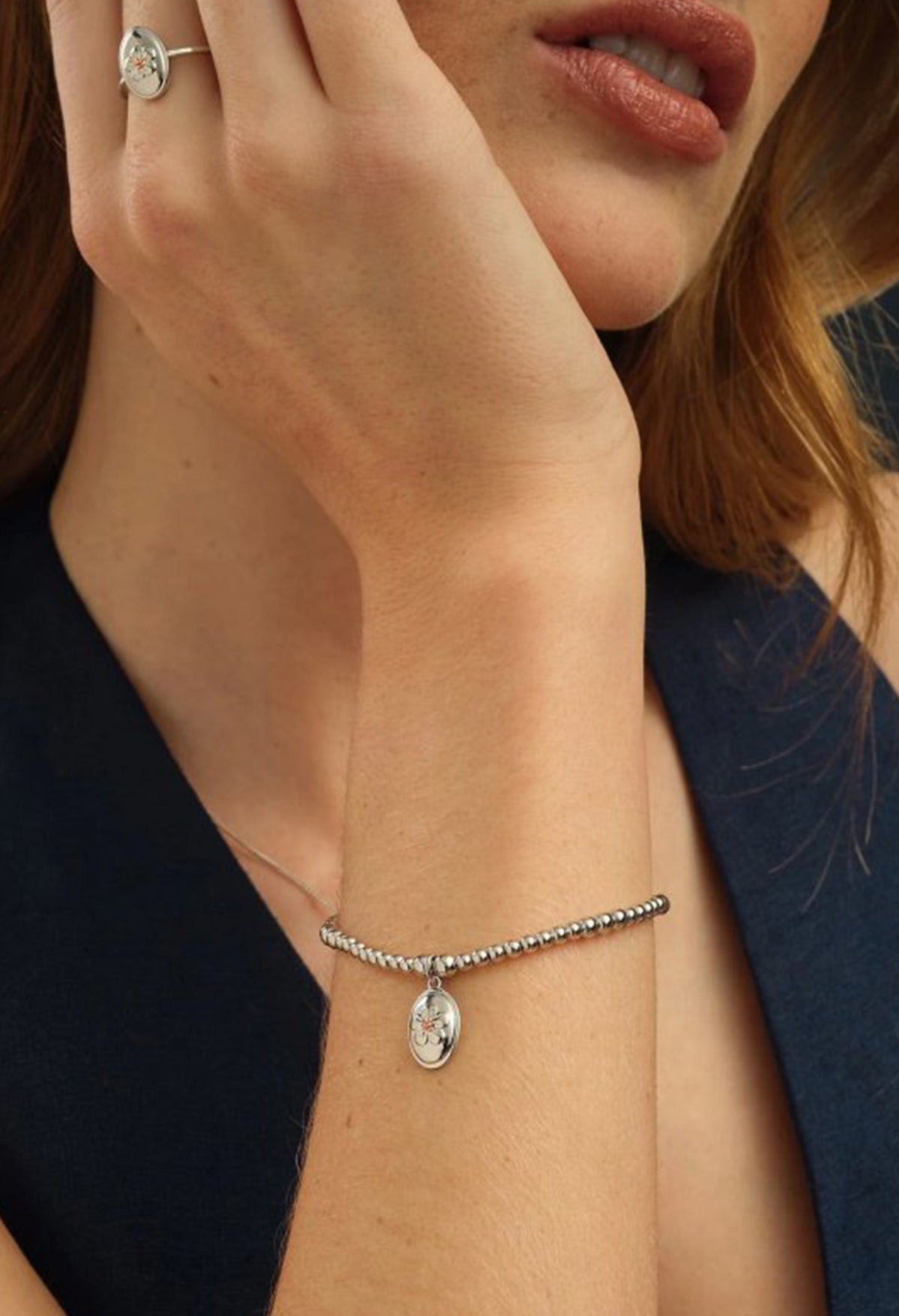 Woman wearing Clogau Natures Wonder bracelet, featuring delicate forget-me-knot charm, paired with matching ring.