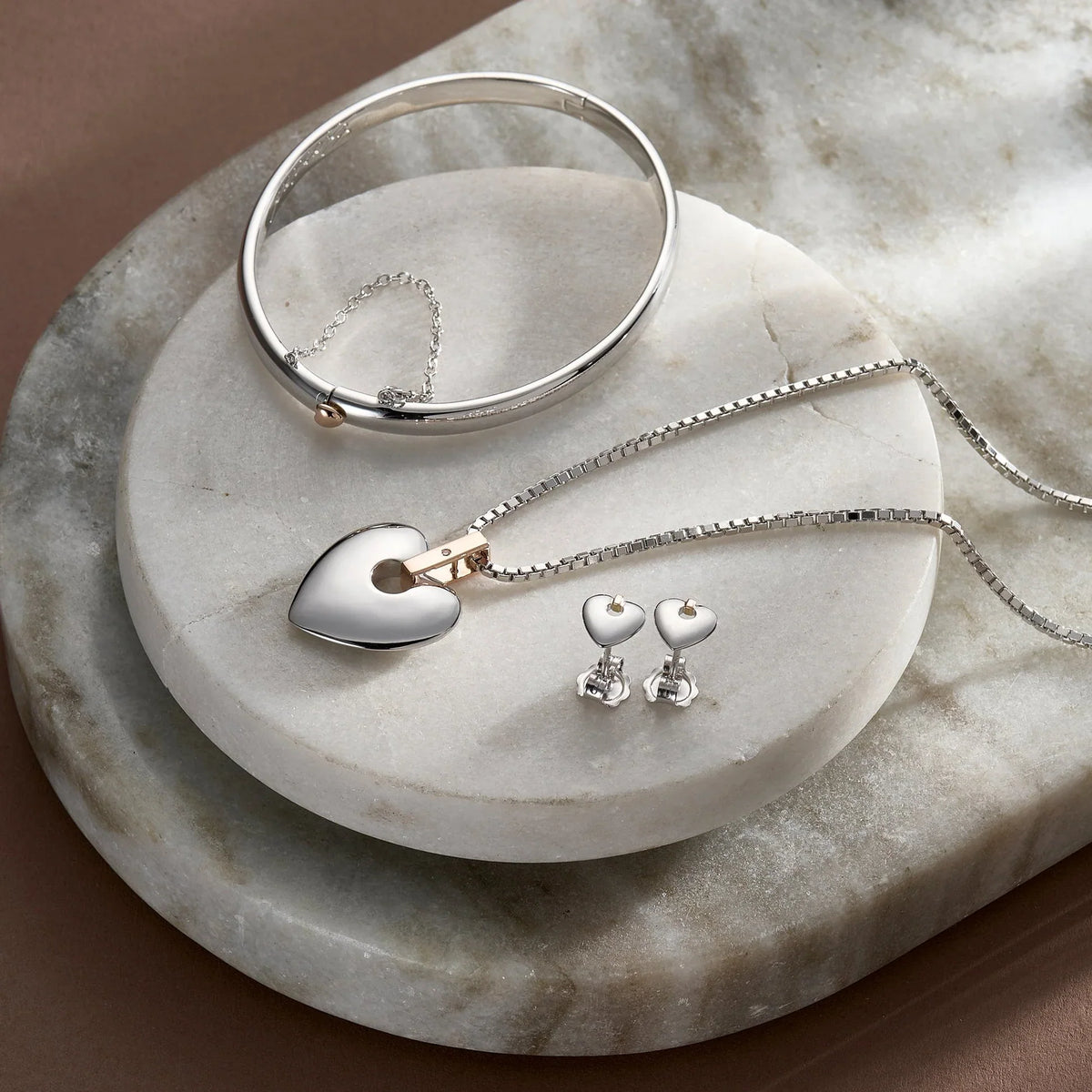 Silver heart jewelry set including a bangle, pendant necklace, and heart-shaped earrings.