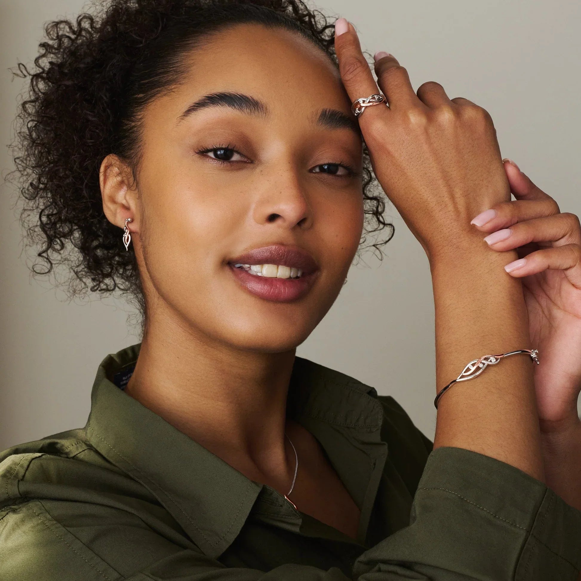 A woman wearing silver jewelry and an olive-green shirt.
