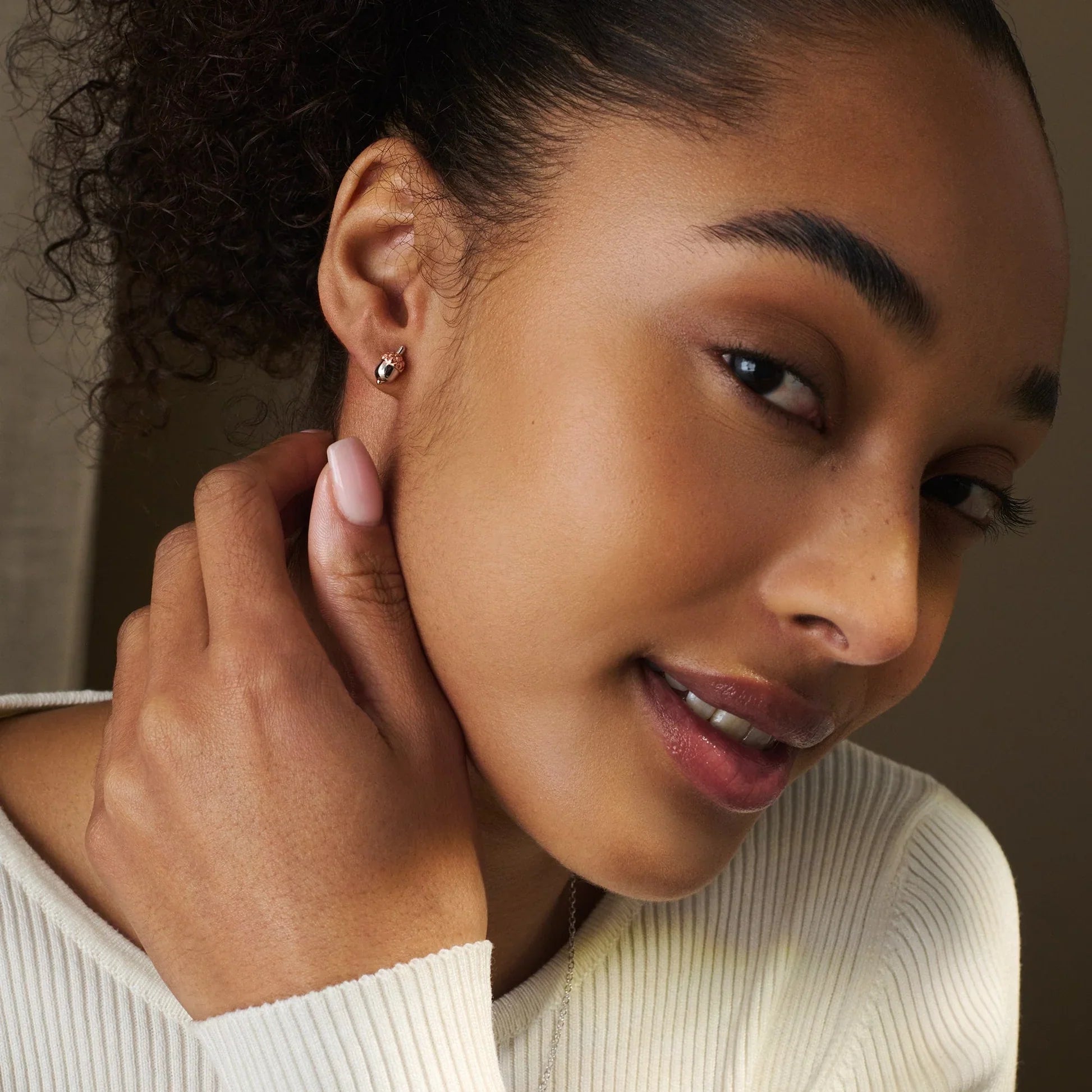 Woman wearing acorn earrings and a white knit sweater.
