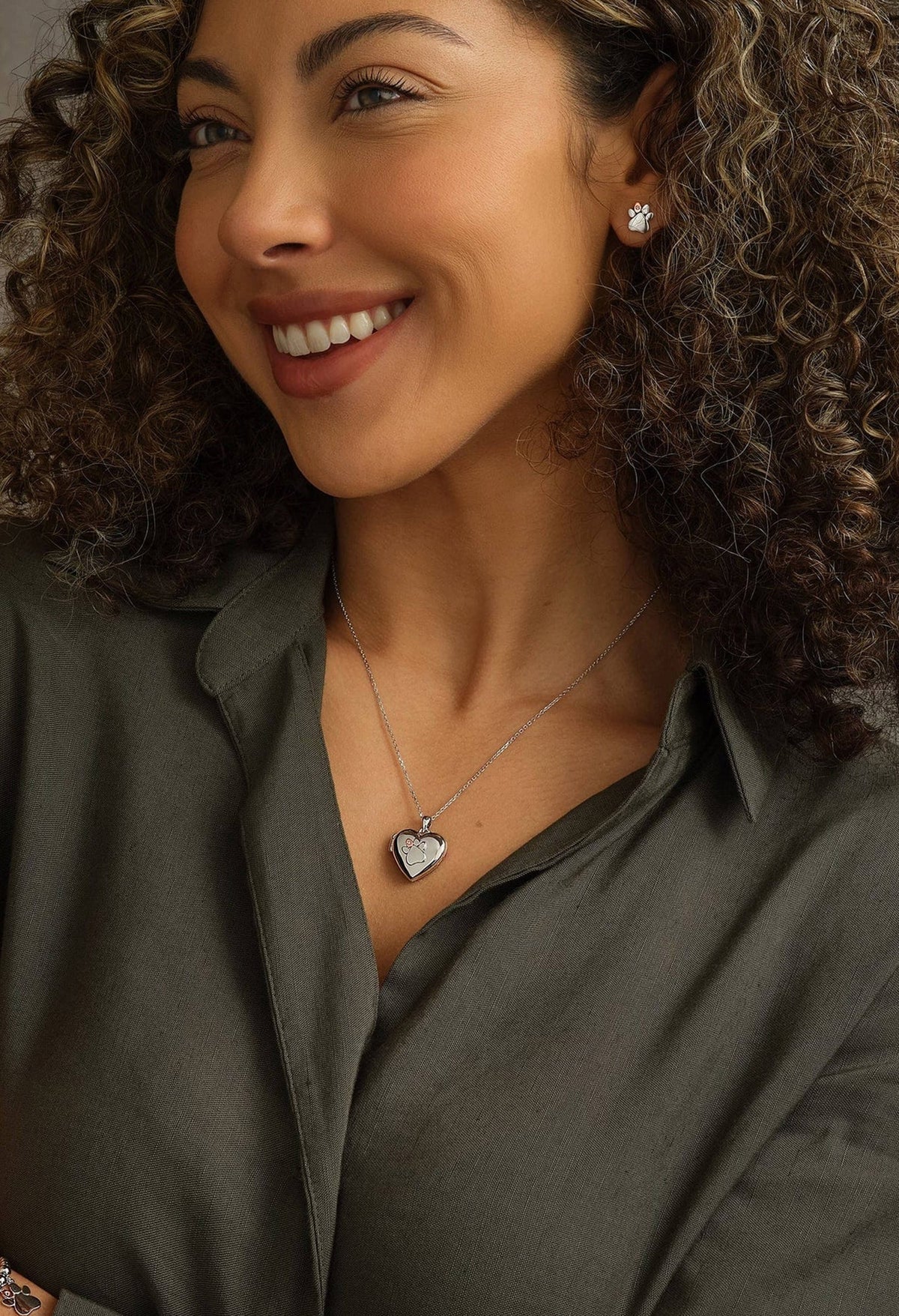 Woman wearing a Paw Print Heart Locket necklace and matching earrings, showing the jewelry design.