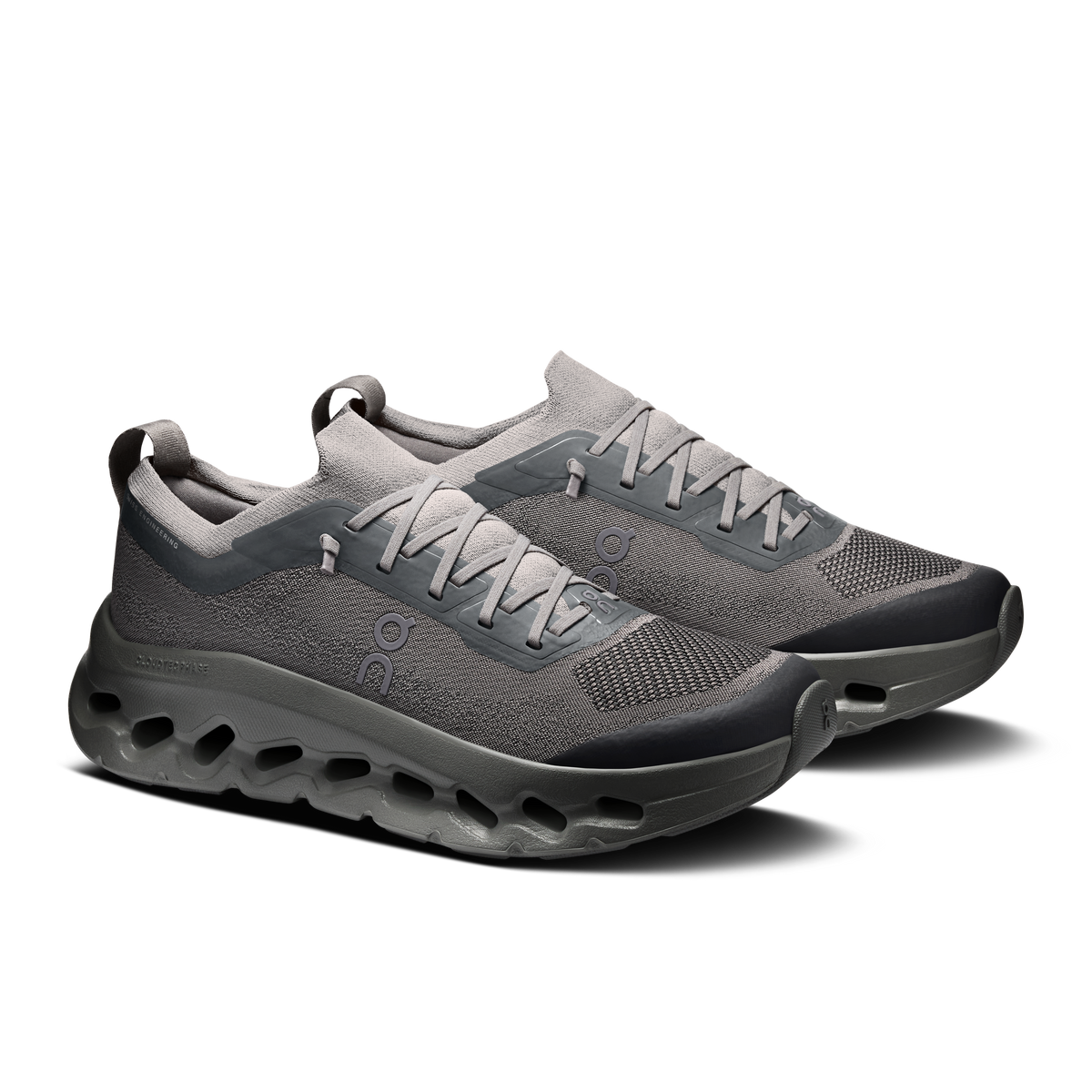 A pair of gray and dark gray athletic sneakers with a knit upper, gray laces, and a thick, cushioned, gel-like sole, shown on a plain white background.