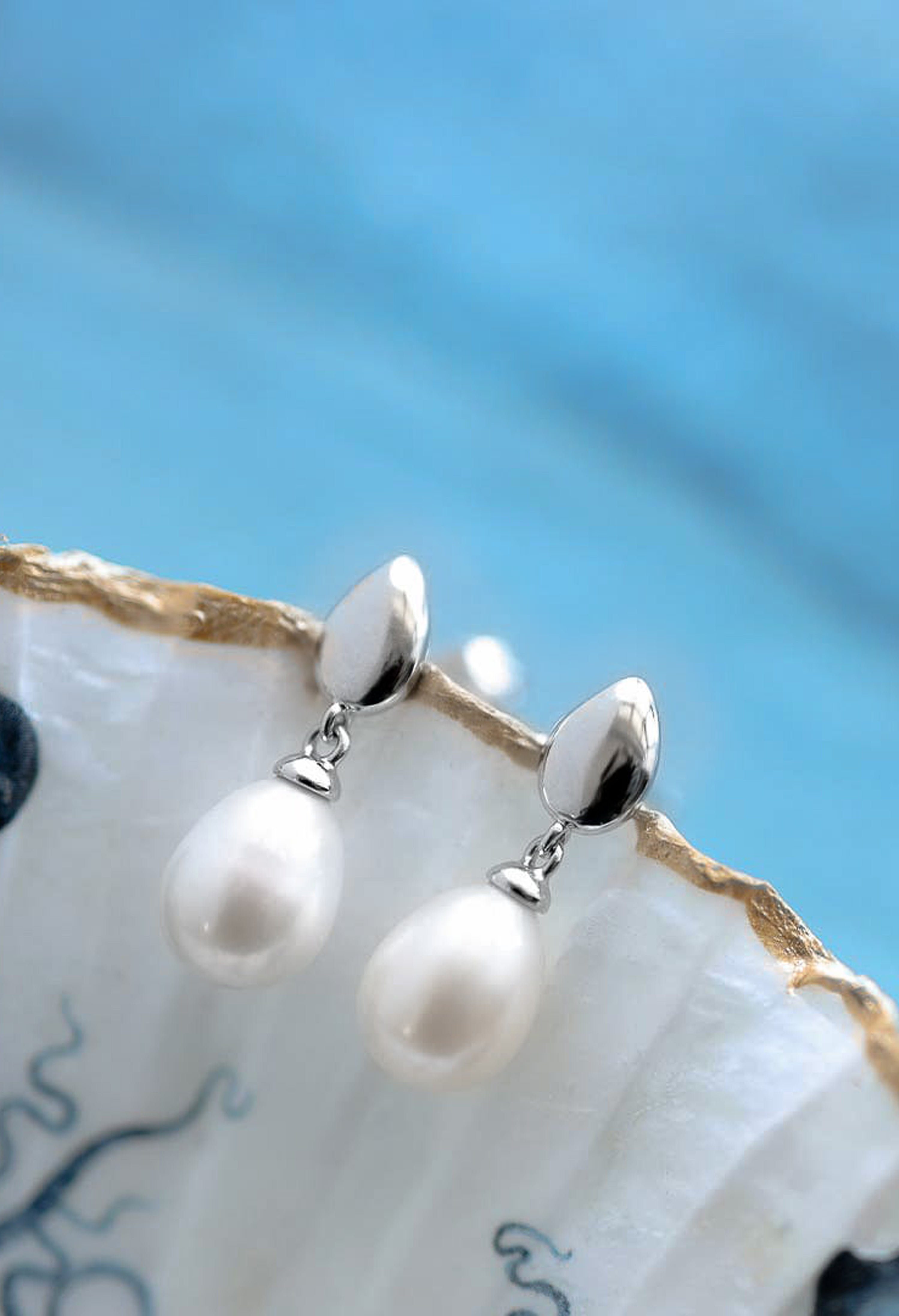 Elegant Kit Heath pearl earrings displayed, showcasing the Coast Pebble design in polished sterling silver. Jewelry detail.
