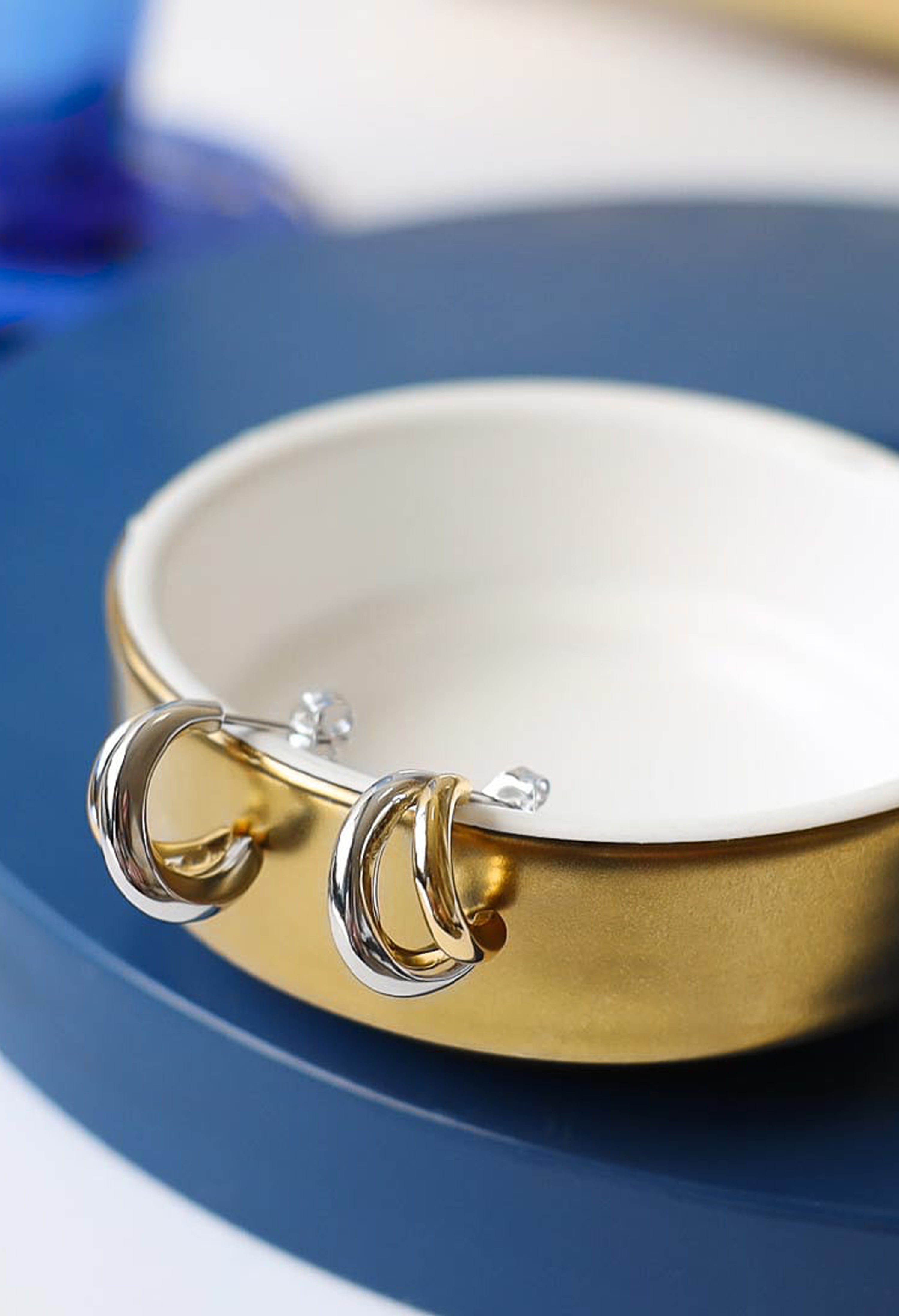 Kit Heath earrings, Bevel Cirque design. Twin hoop earrings with silver and gold links, displayed in dish.