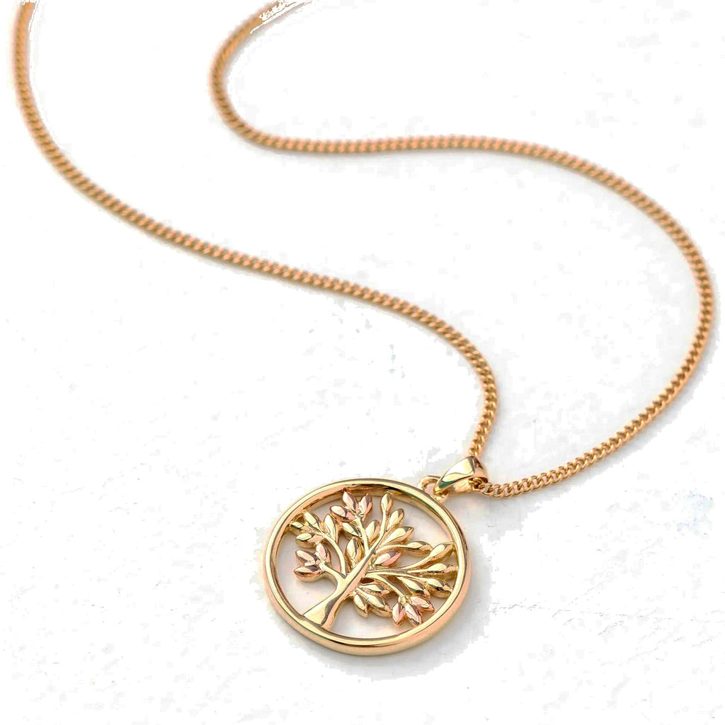 Gold necklace with tree pendant on white.