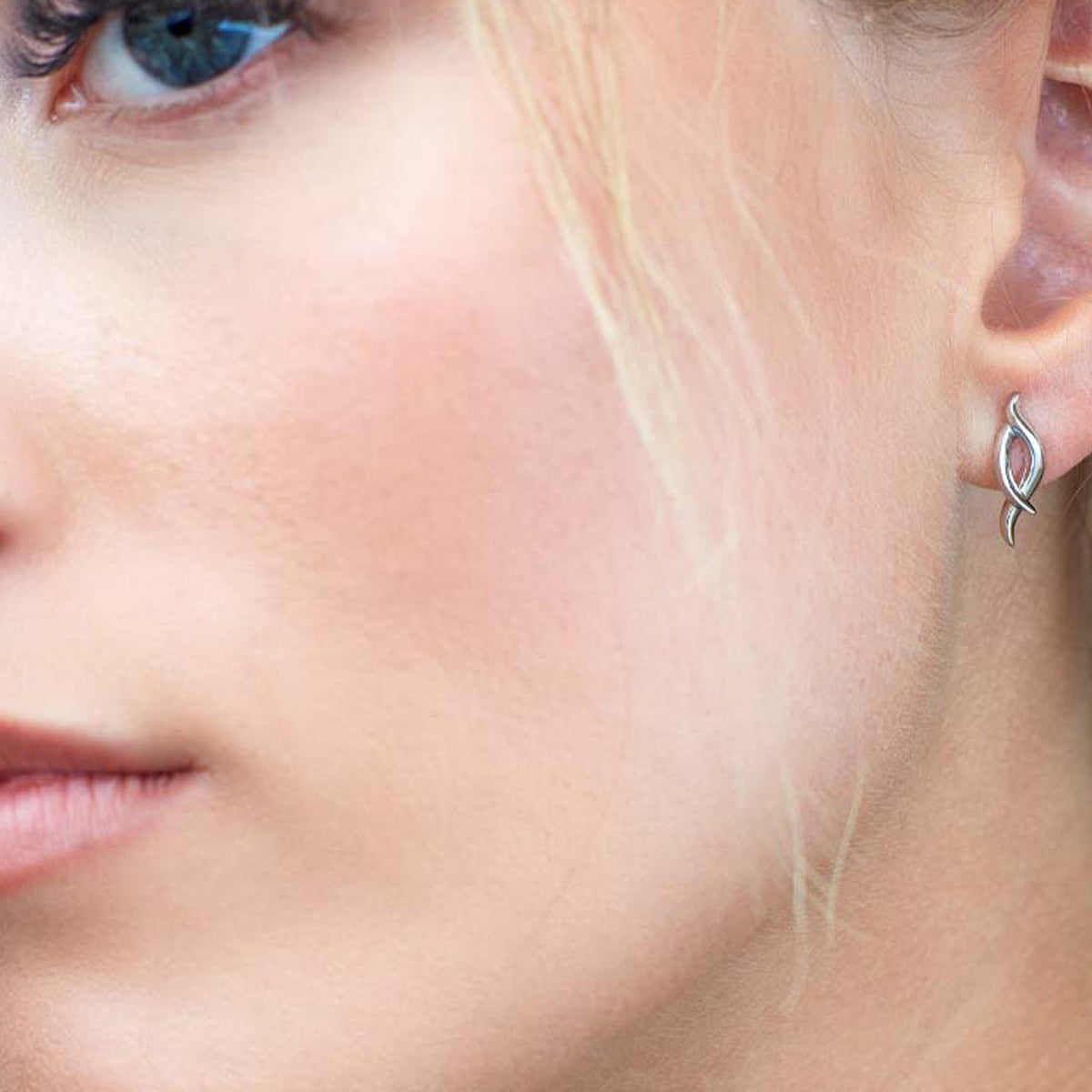 Close-up of a woman wearing the Kit Heath Entwine Twine Twist Stud Earrings, showcasing earring design and fit.