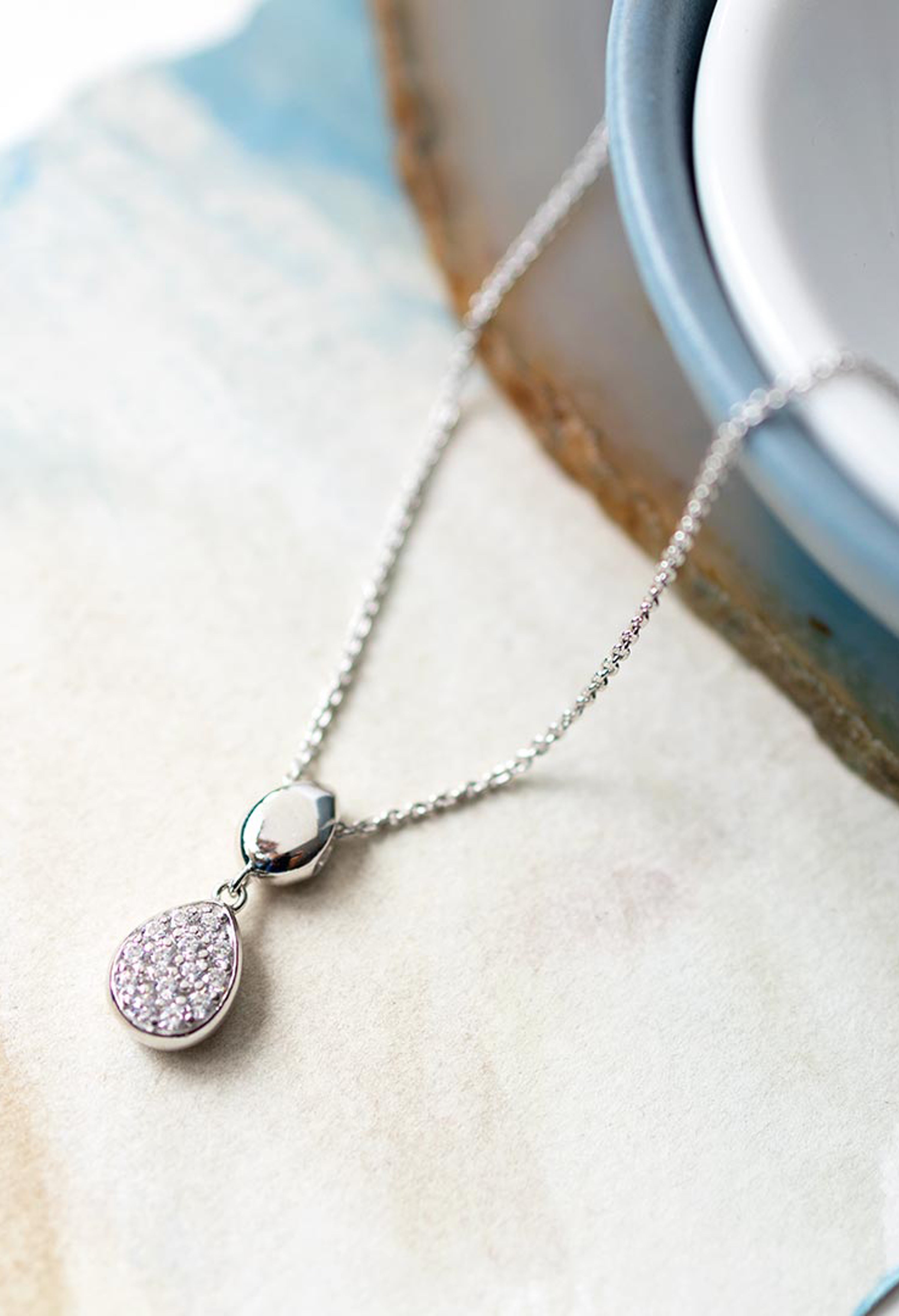 Close-up showcasing the Kit Heath silver necklace with double droplet pendant and pave CZ stones, stylish jewelry detail.