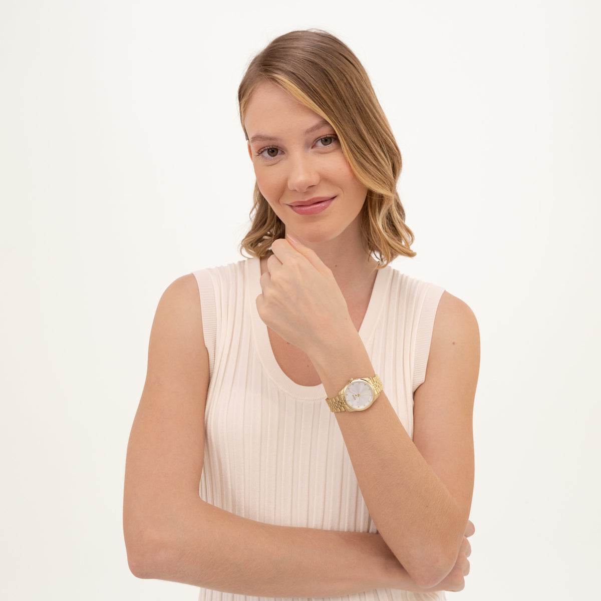 Blonde woman wearing a cream top and gold watch.
