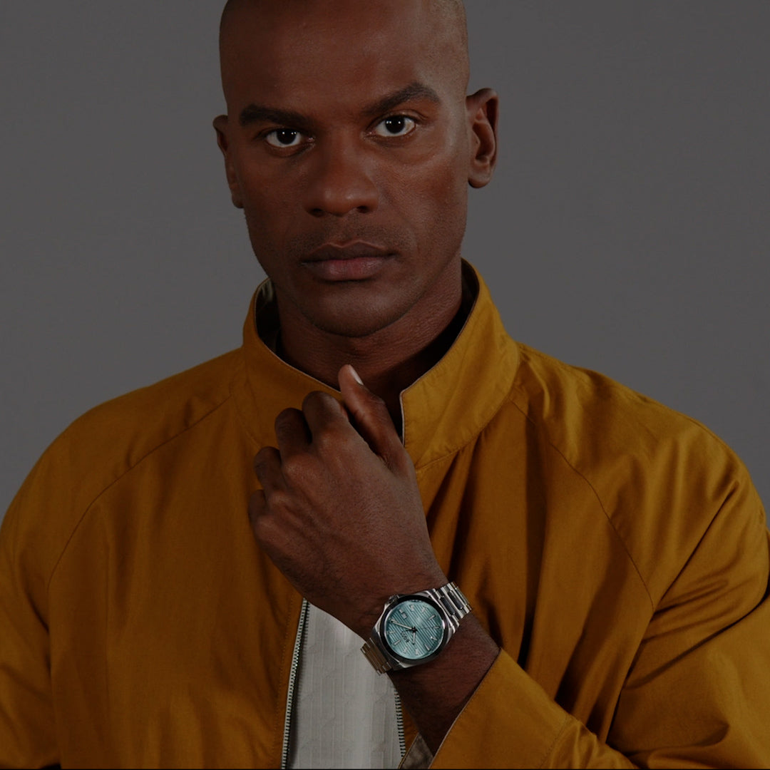 Stainless steel watch on wrist; Boss Strike turquoise dial shown on model, luxury style.