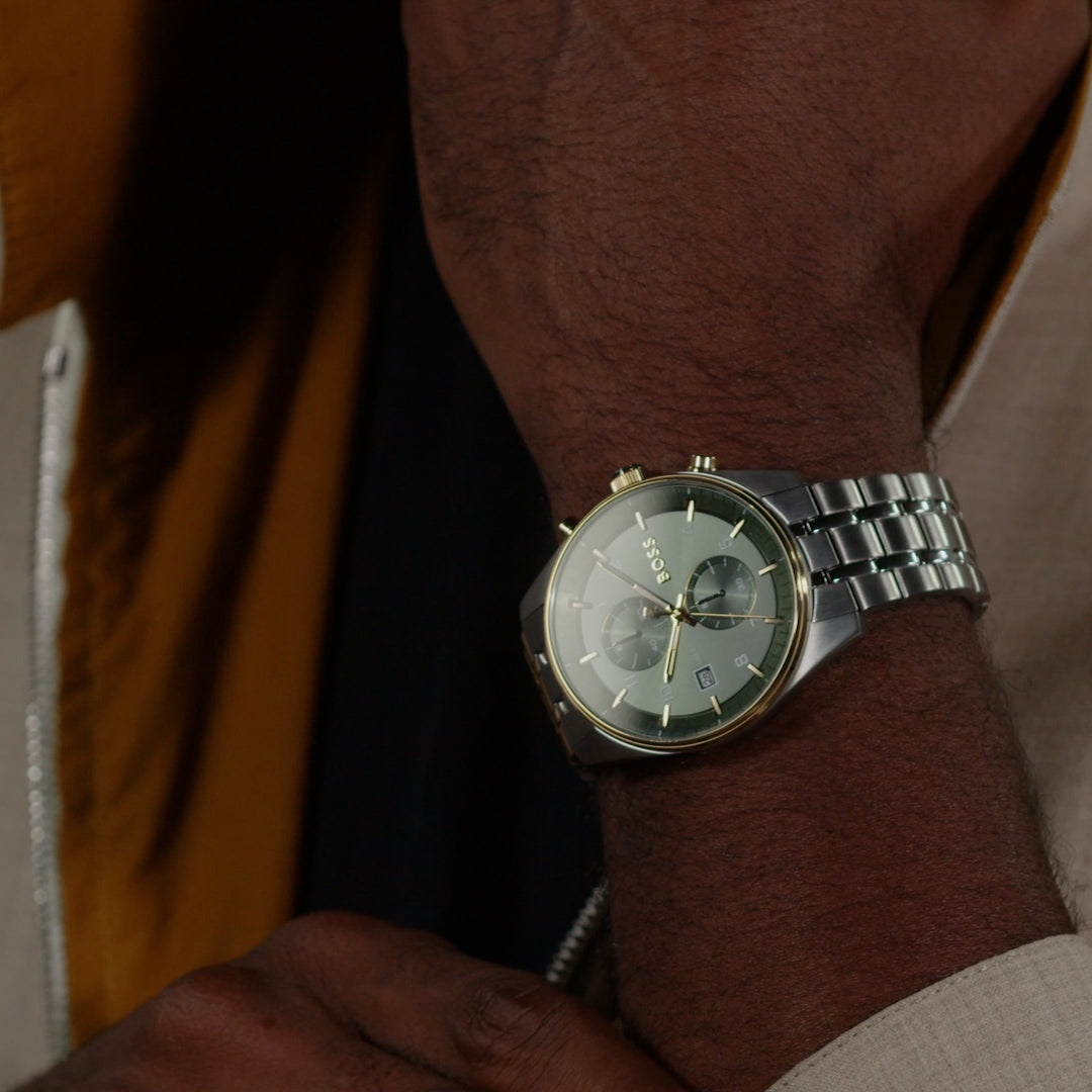 Man wearing a BOSS Skytraveller watch. Stainless steel bracelet, green dial. Watch face detail.