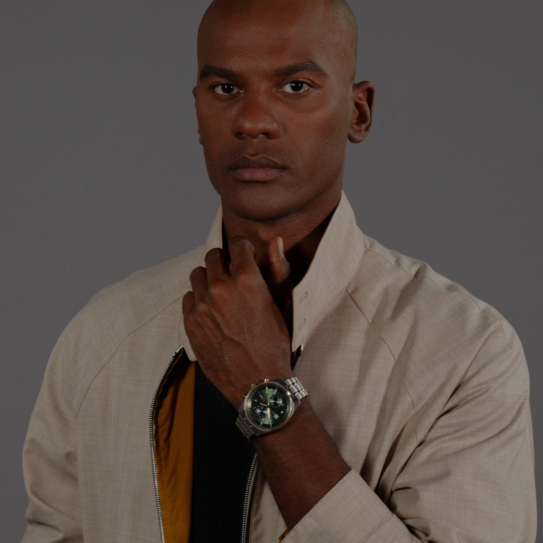 Stylish man wearing the BOSS Skytraveller watch with a green dial and stainless steel bracelet, showcasing sophisticated