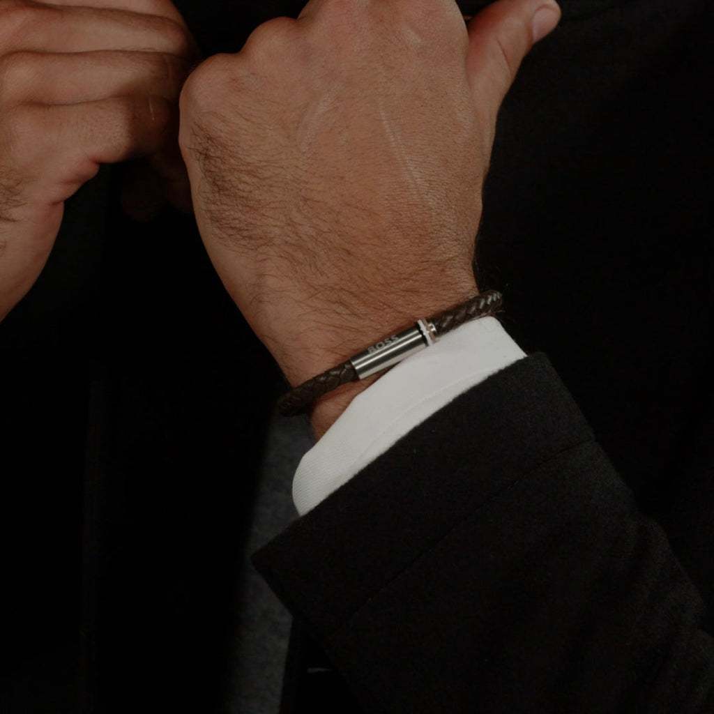 Close-up of BOSS Ares bracelet on wrist; brown braided leather & stainless steel highlights stylish accessory.
