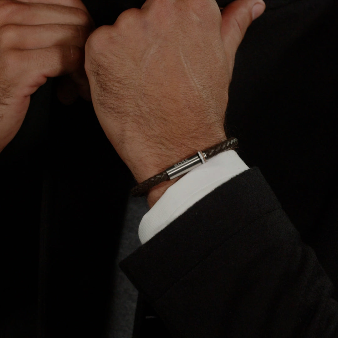 Close-up of BOSS Ares bracelet on wrist; brown braided leather & stainless steel highlights stylish accessory.