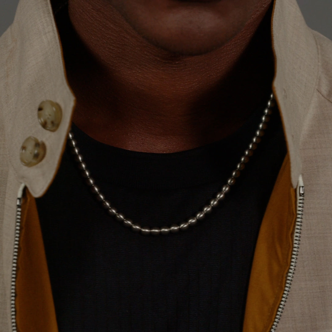 Man wearing a BOSS stainless steel necklace. Minimalist style and subtle jewelry accent.