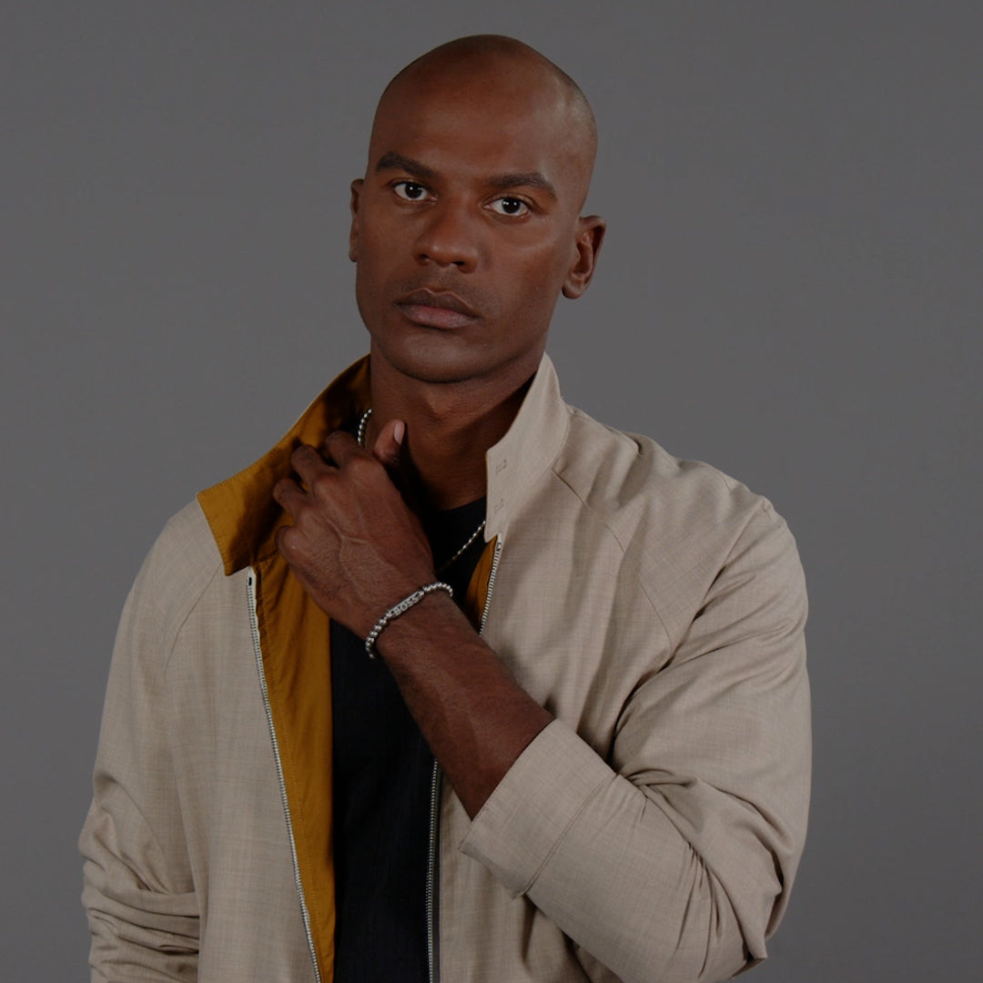 Man wearing a BOSS bracelet, showcasing stainless steel sphere design. Jewelry accentuates his casual, yet stylish, jacket.