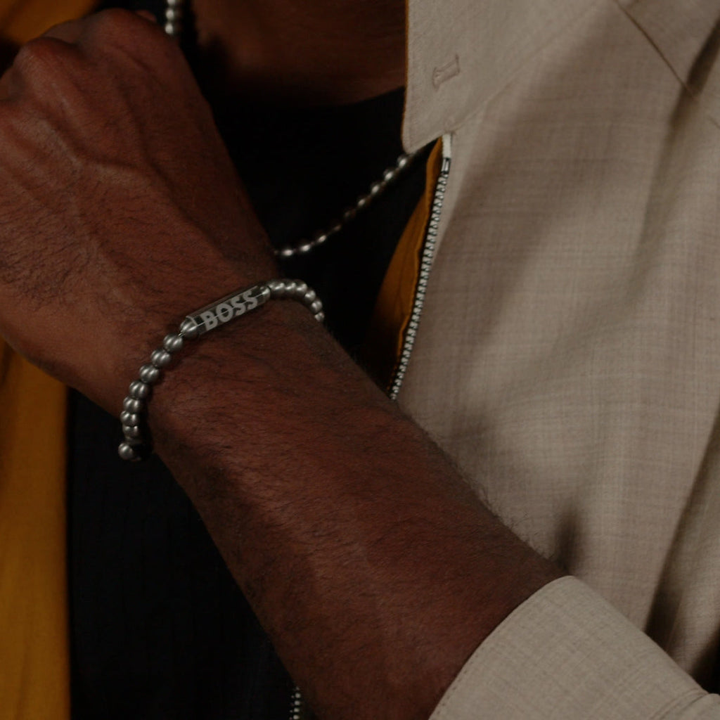 Stainless steel BOSS bracelet on wrist. Shows design & fit. Features "BOSS" logo detail. Mens jewelry product shot.