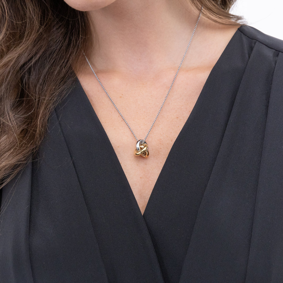 Woman wearing a silver and gold linked necklace with a black dress.