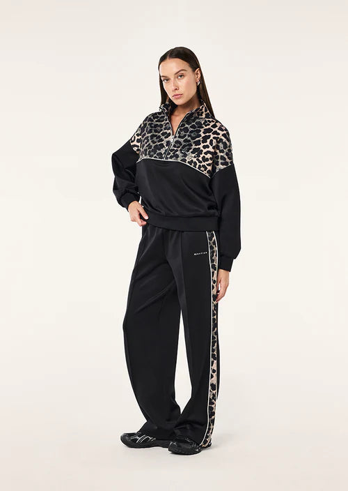 Person wearing a black tracksuit with leopard print accents on a white background