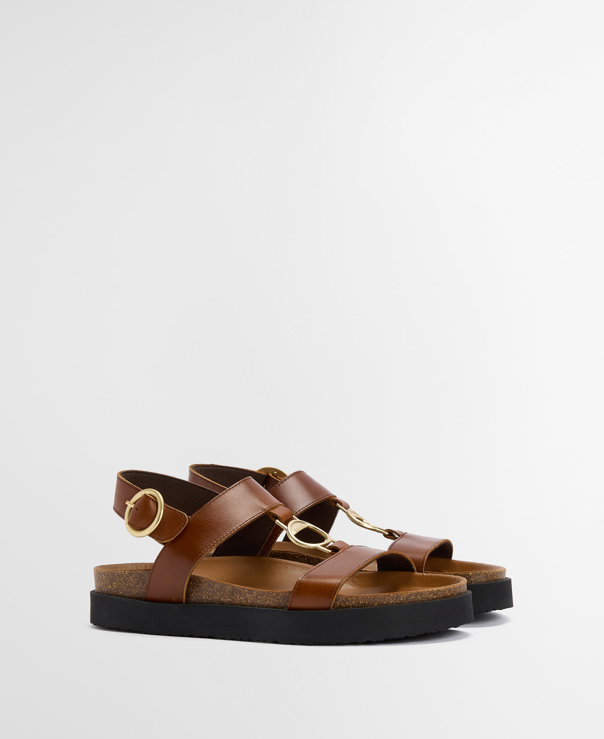 Brown sandals with gold buckles on a light gray background