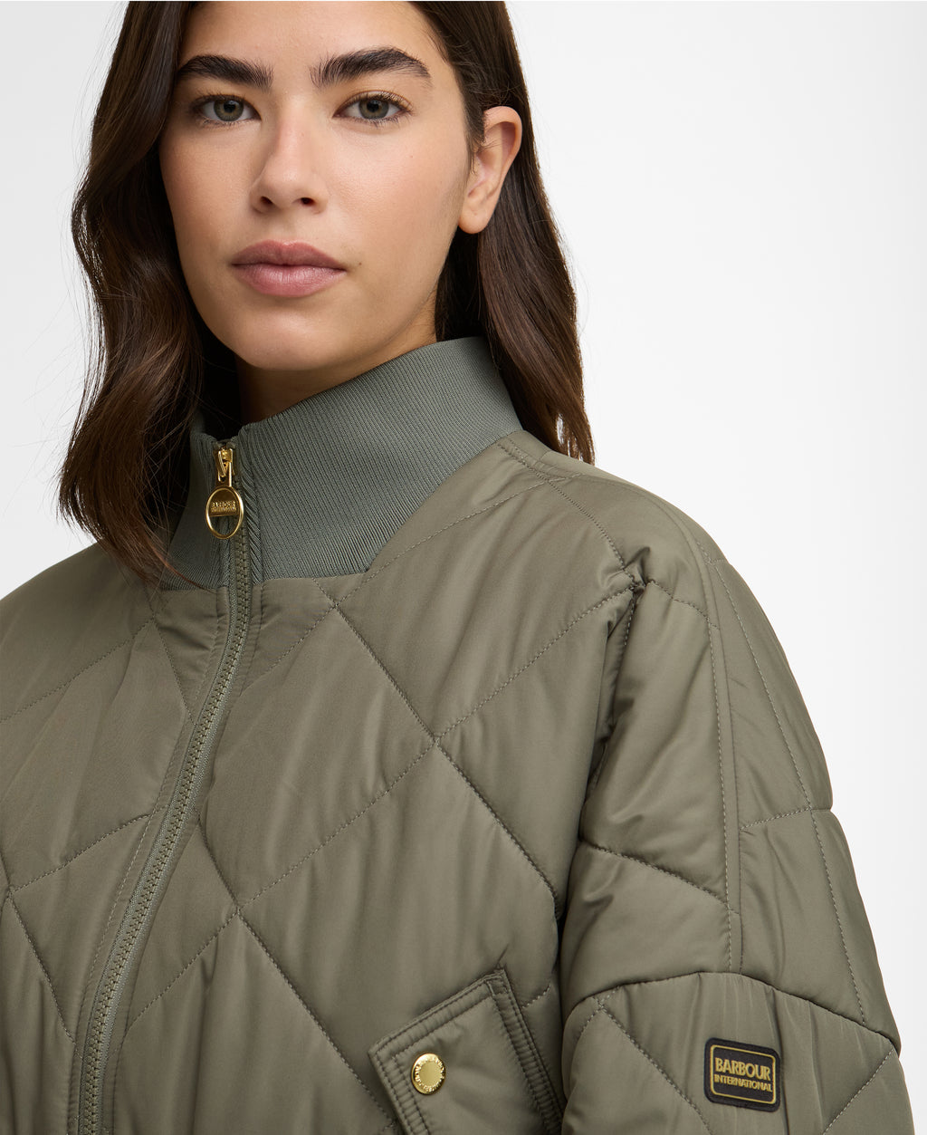 Person wearing a green quilted jacket with a brand logo on a white background