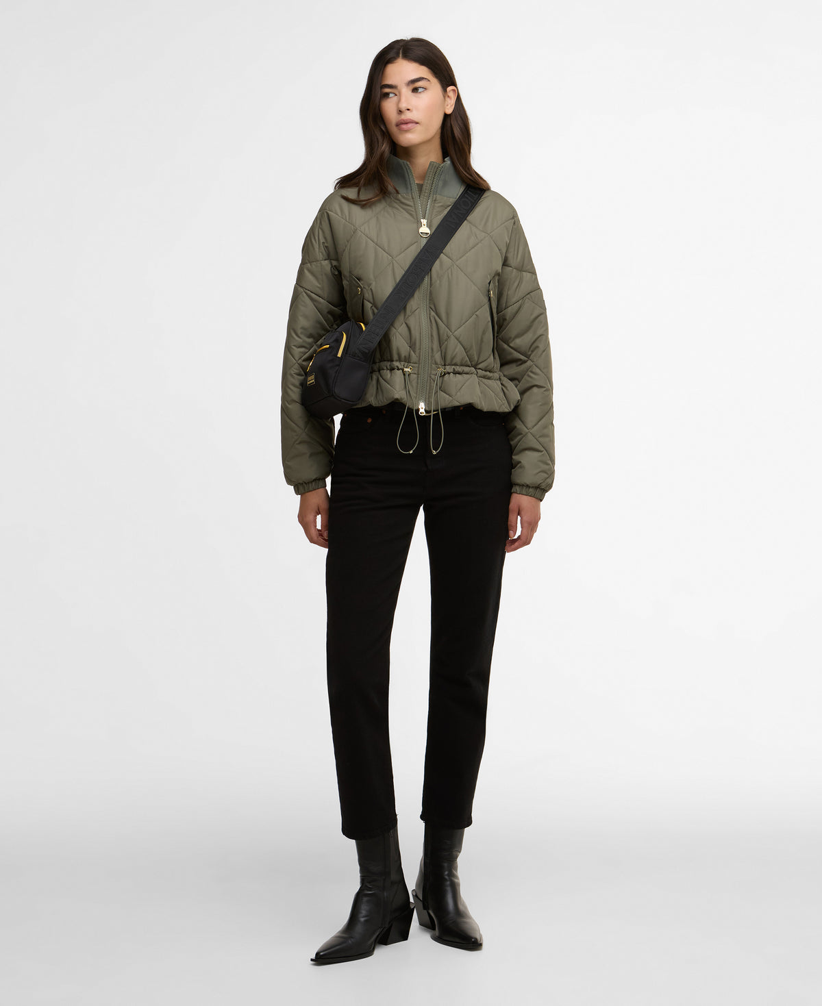 Woman wearing a green jacket and black pants on a white background