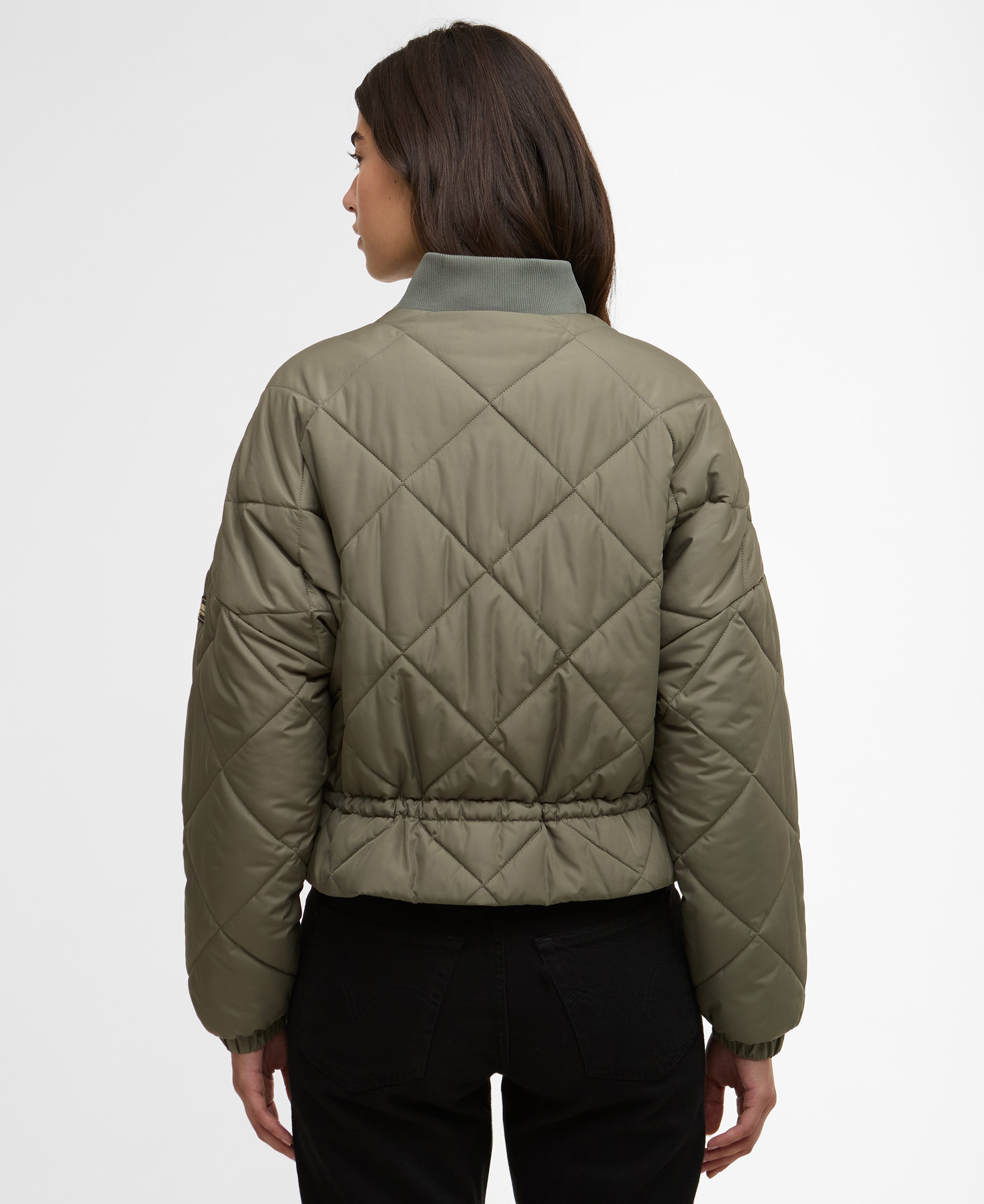 Person wearing a quilted green jacket on a white background