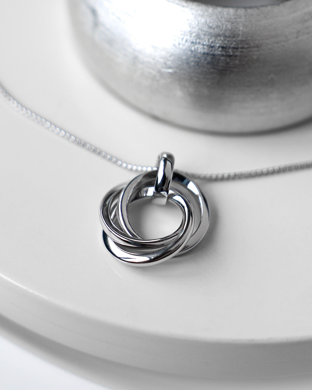 Bevel Trilogy Necklace on a styled background