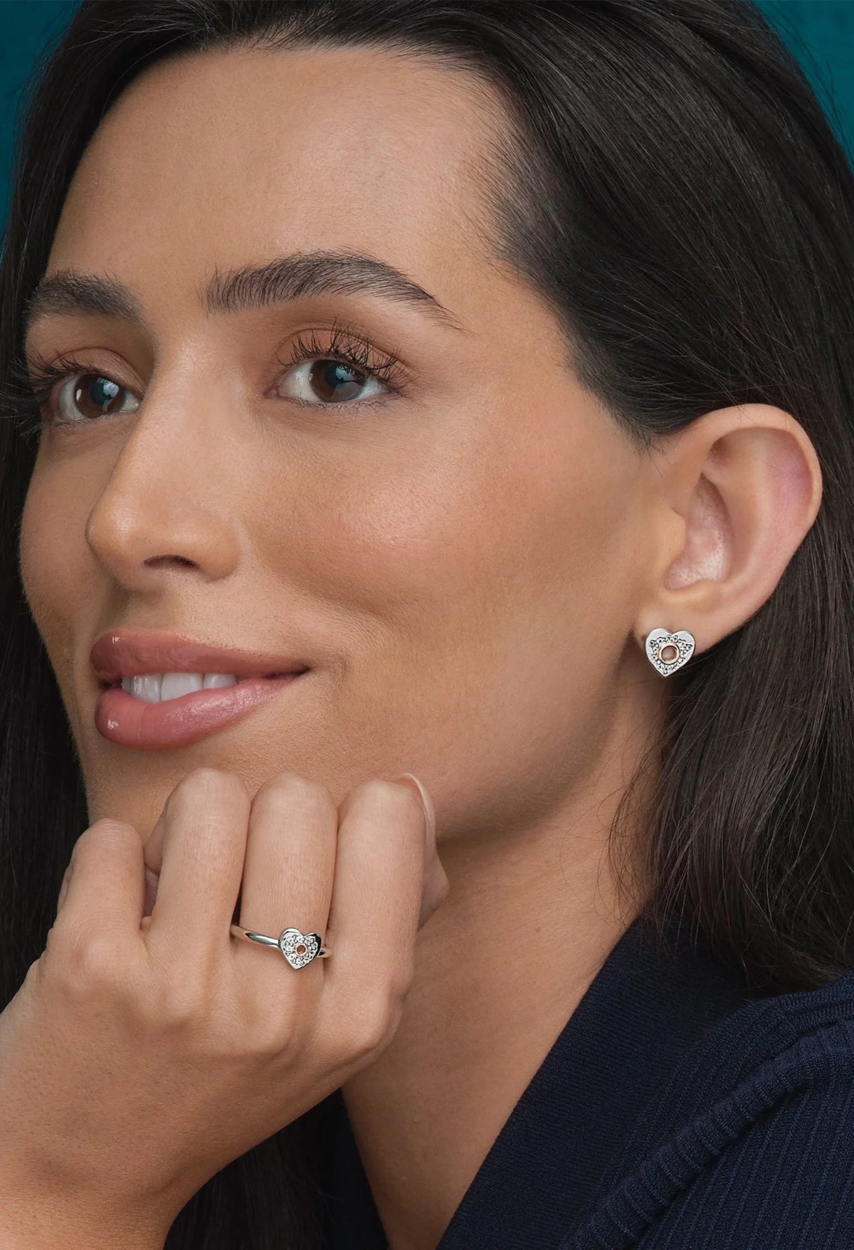 Woman wearing Clogau Cariad heart stud earrings and matching ring, showcasing jewelry design and detail.