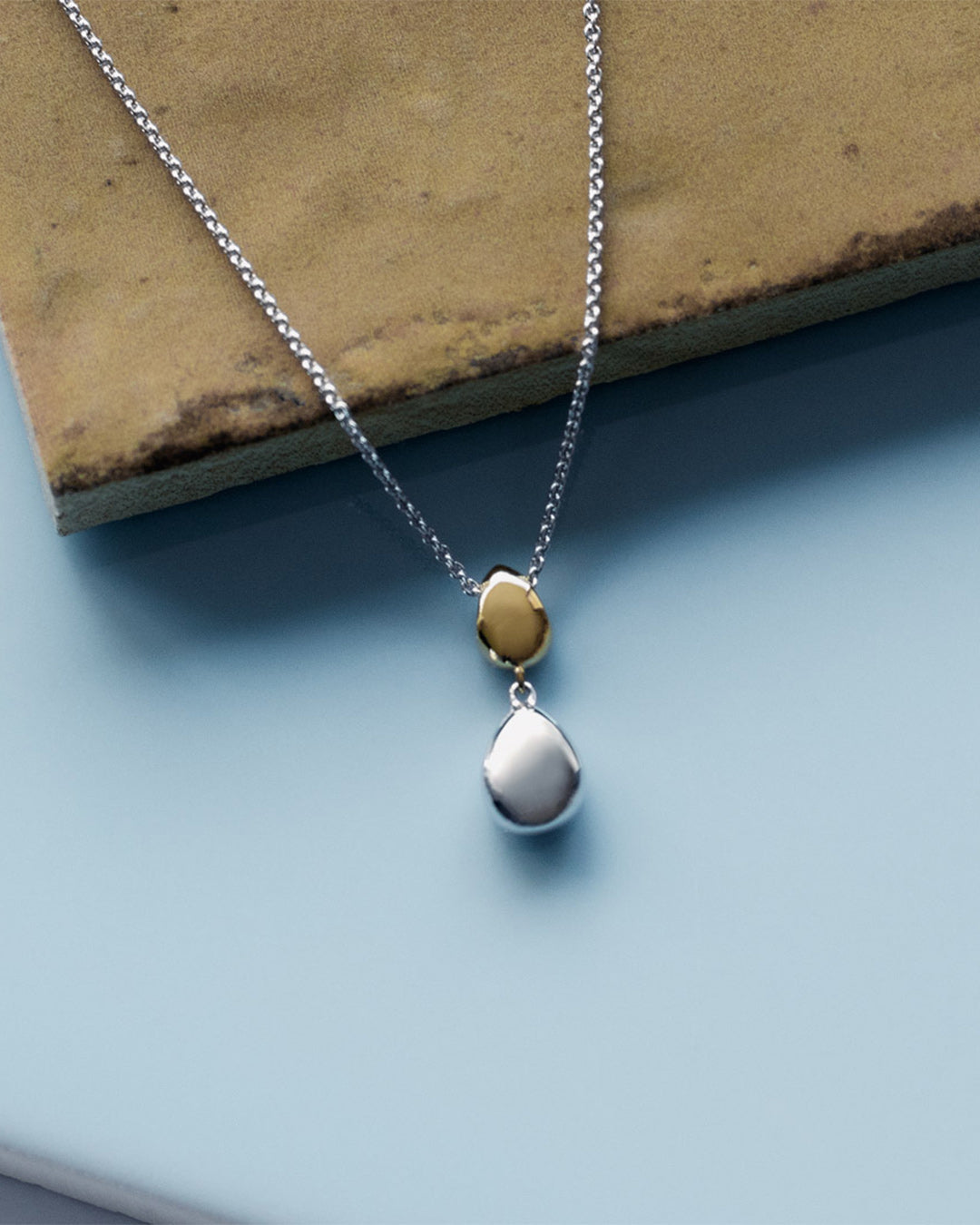 Coast Pebble Golden Necklace on a styled background