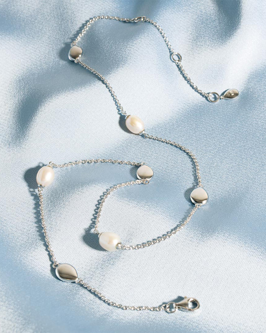 Coast Pebble Pearl Station Necklace on a styled background