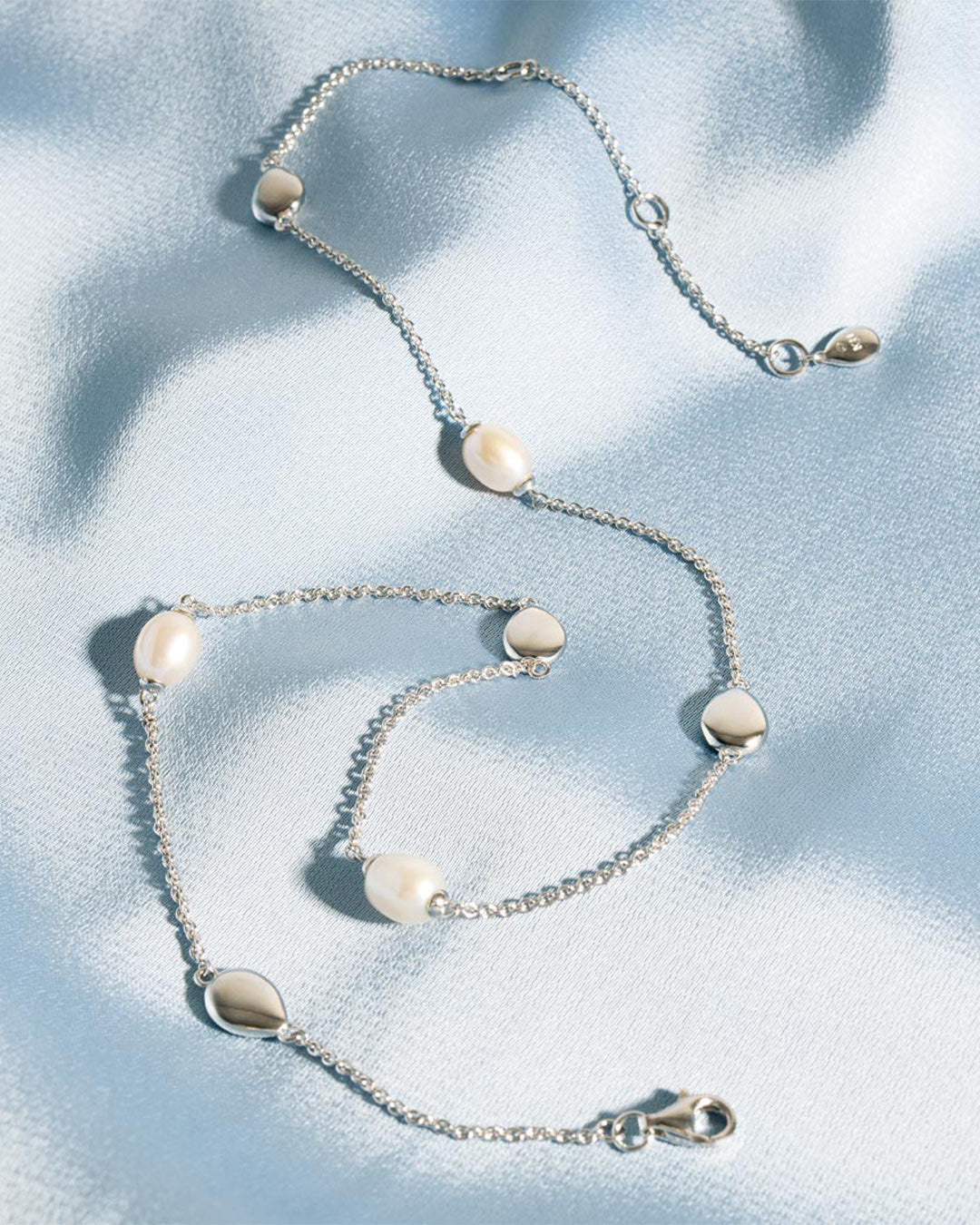 Coast Pebble Pearl Station Necklace on a styled background