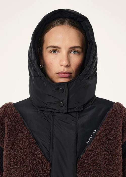 Person wearing a black hooded jacket with a brown garment underneath on a white background
