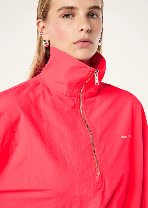 Person wearing a red jacket with a brand logo on a plain background