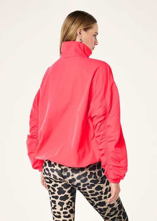 Person wearing a bright pink jacket and leopard print pants on a white background